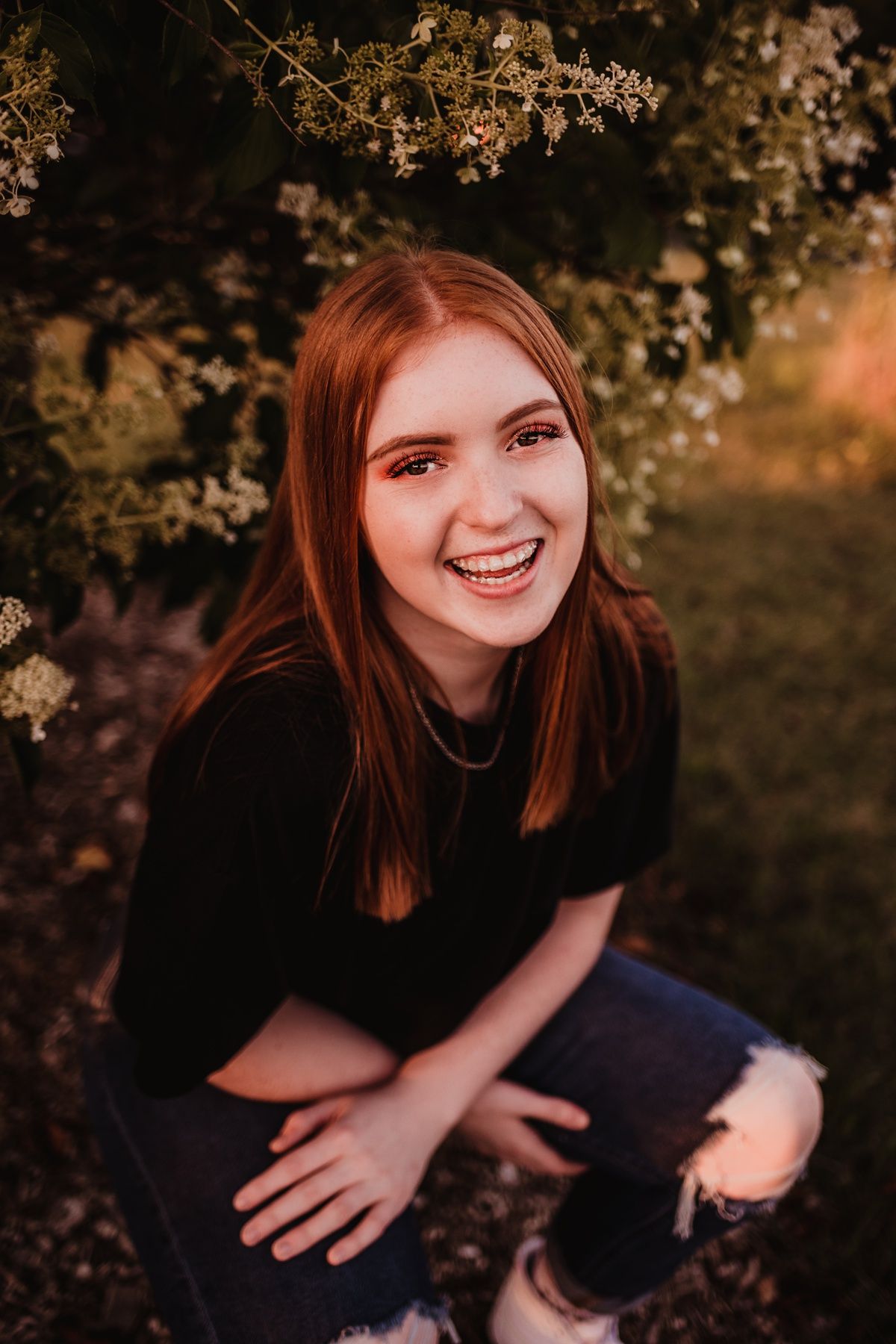 Casual outdoor portrait near blooming flowers at golden hour.