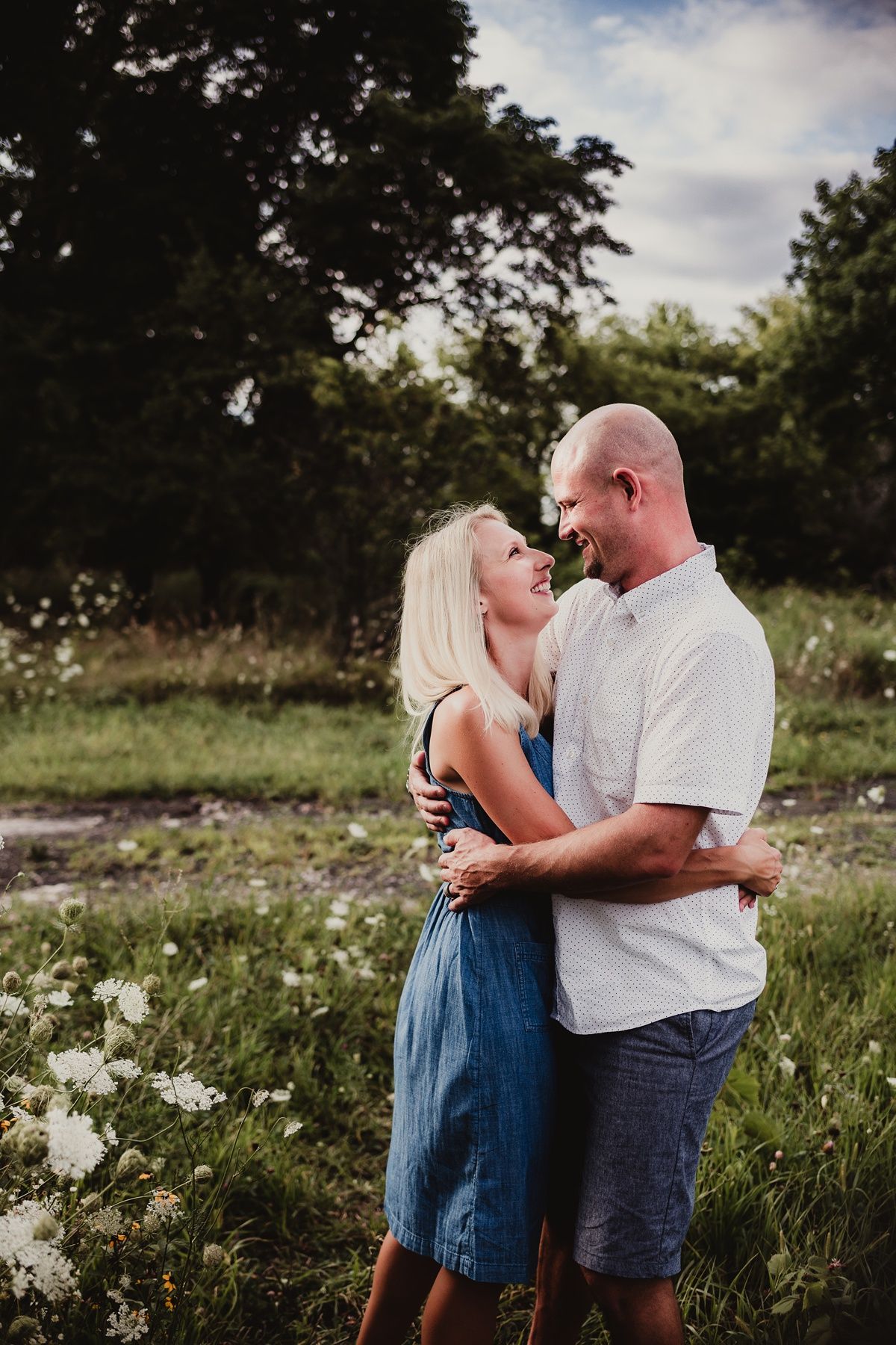 A romantic couple embraces in a wildflower field on a summer day.