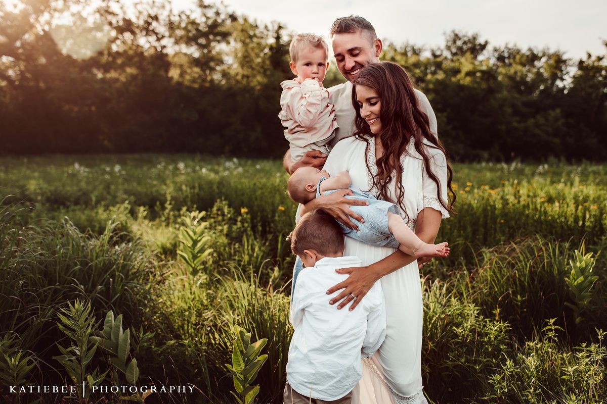 Family embracing in golden sunset light in natural outdoor setting.