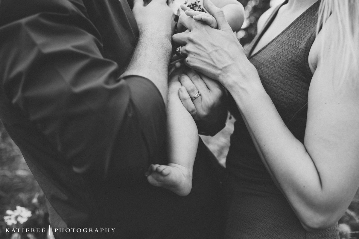 Black and white close up photo of hands lovingly holding a baby.