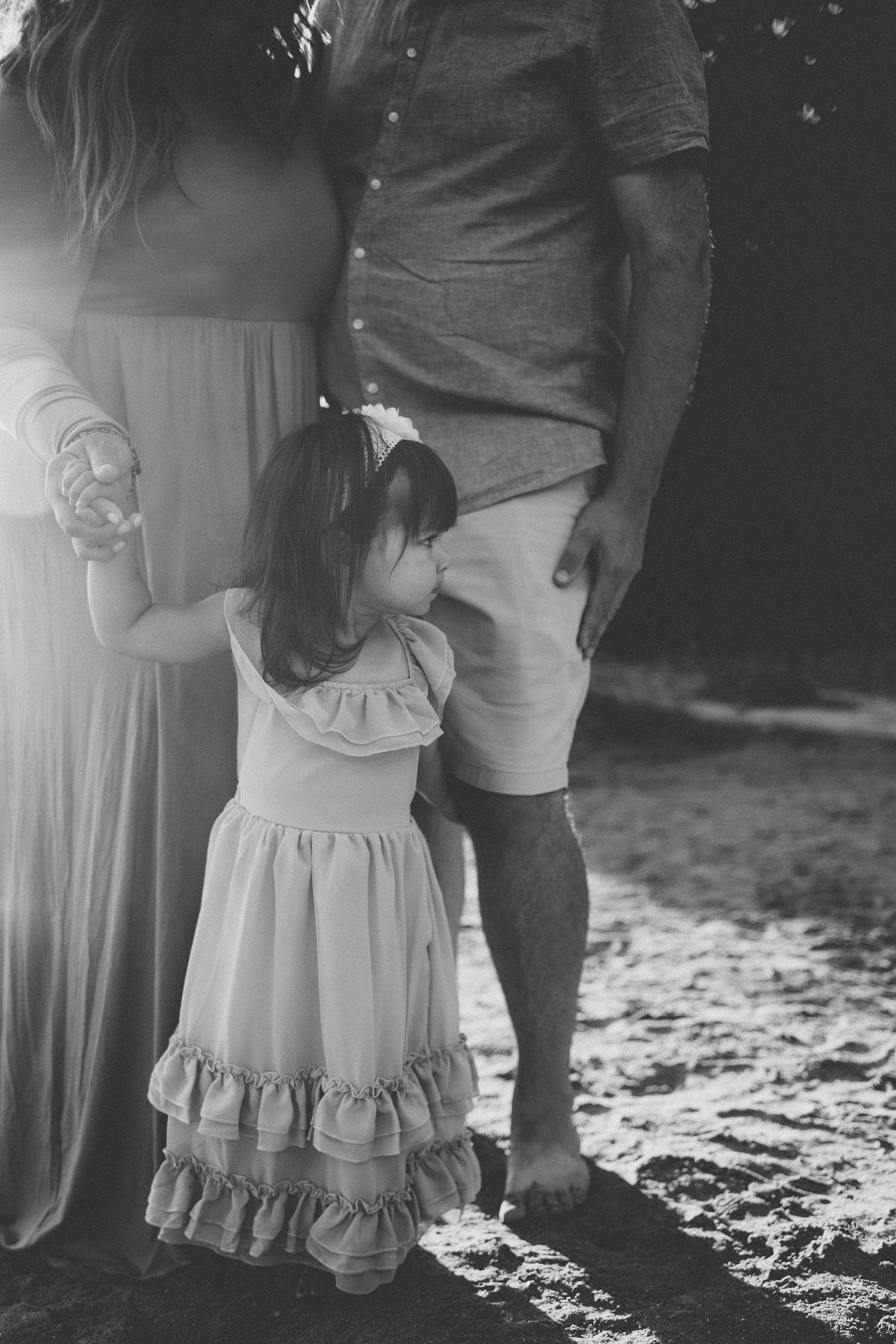 Black and white portrait of a family standing together on a beach.