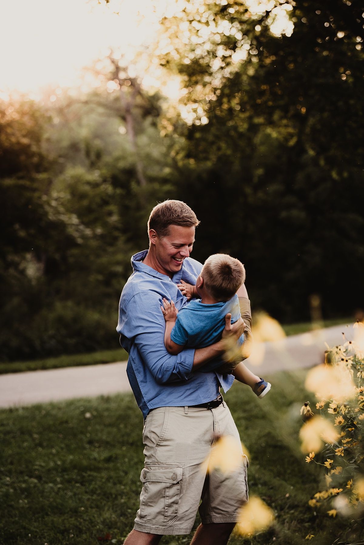 Sunlit outdoor portrait with bokeh effect and yellow flowers in background.