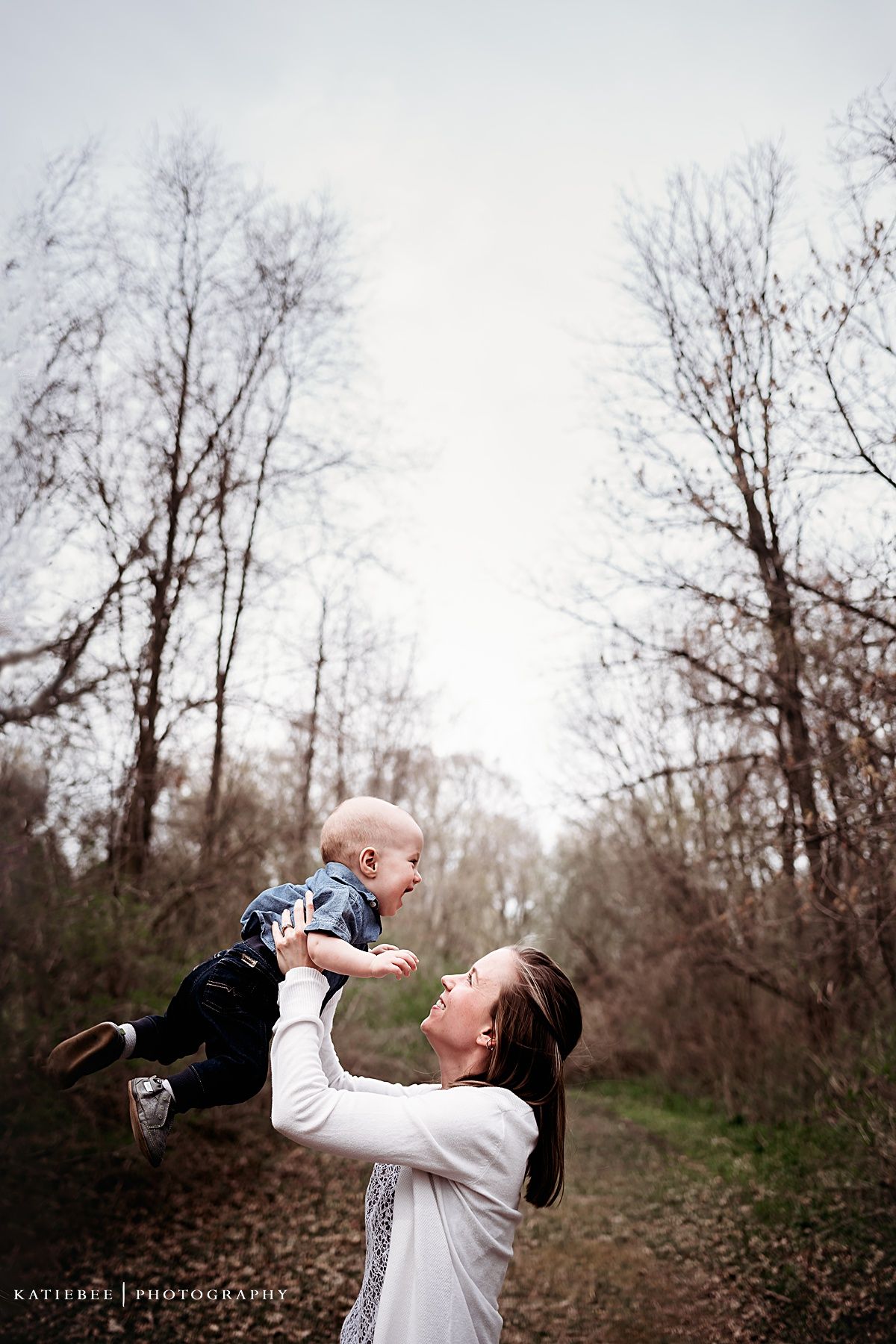 Joyful outdoor portrait capturing playful lift moment against winter trees.