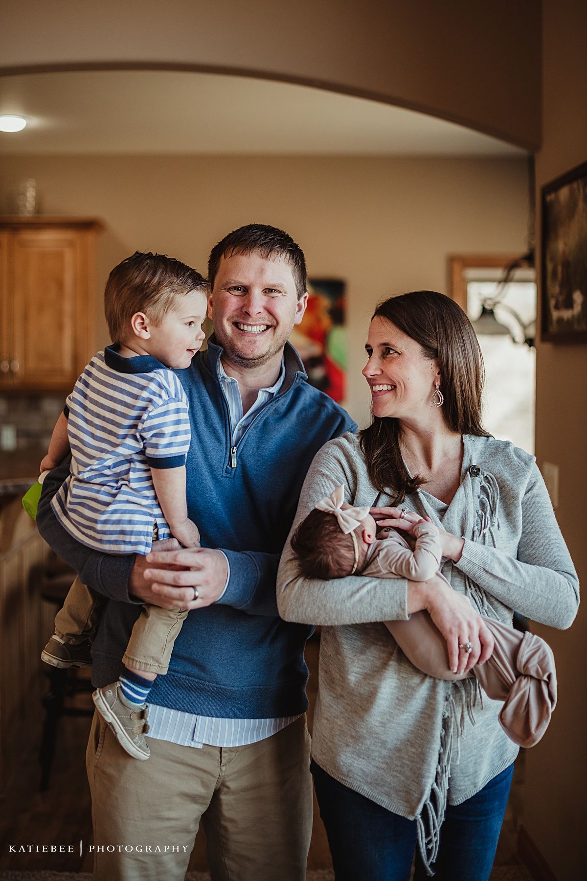 Family portrait in home kitchen showing warm embrace and genuine smiles.