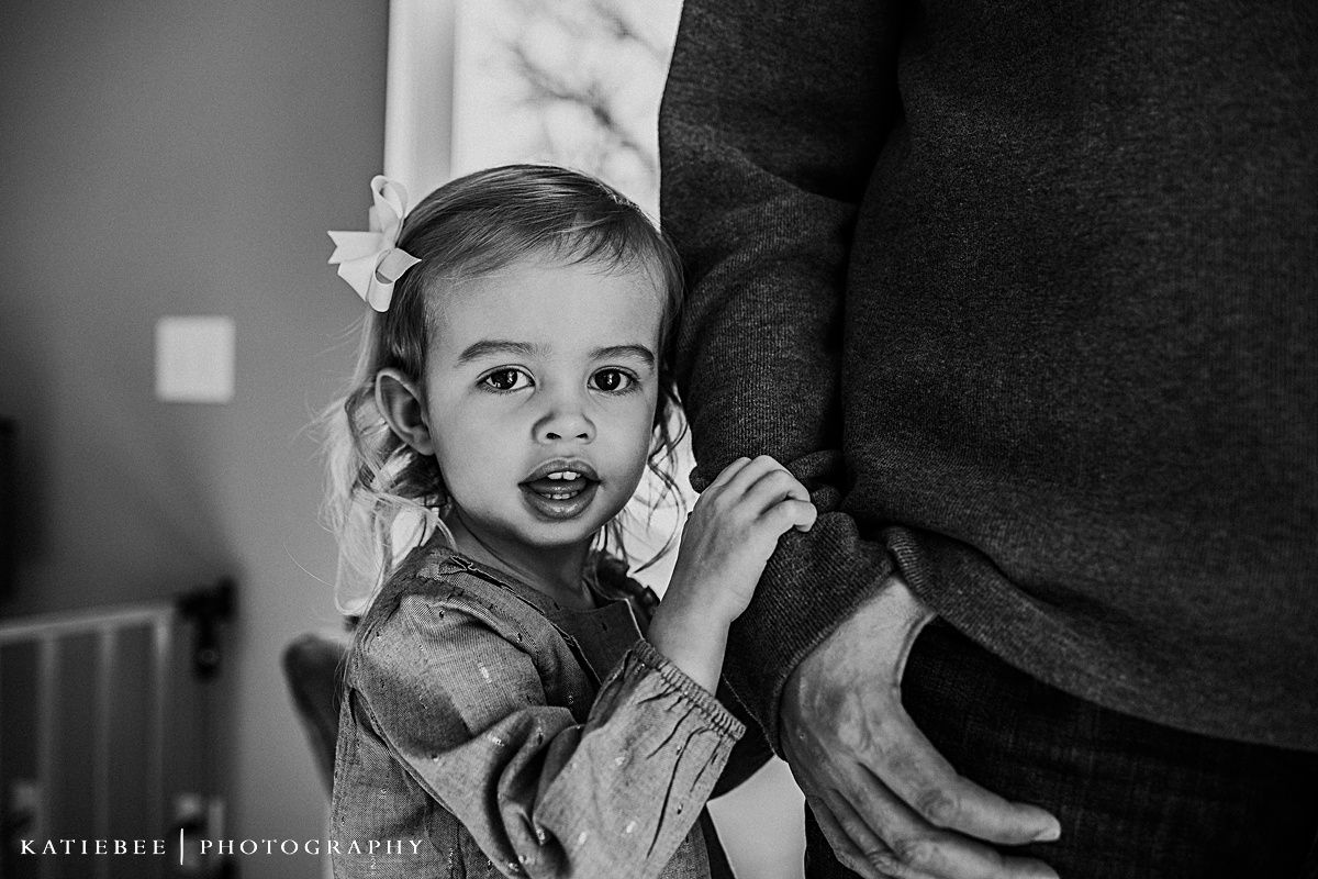 Black and white close-up portrait of a toddler in a grey sweater showing excitement.