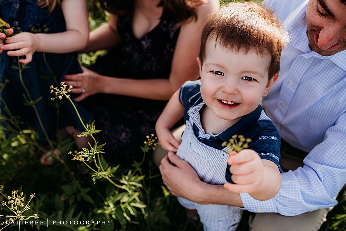A joyful outdoor family moment captured with sunlit wildflowers in the background.