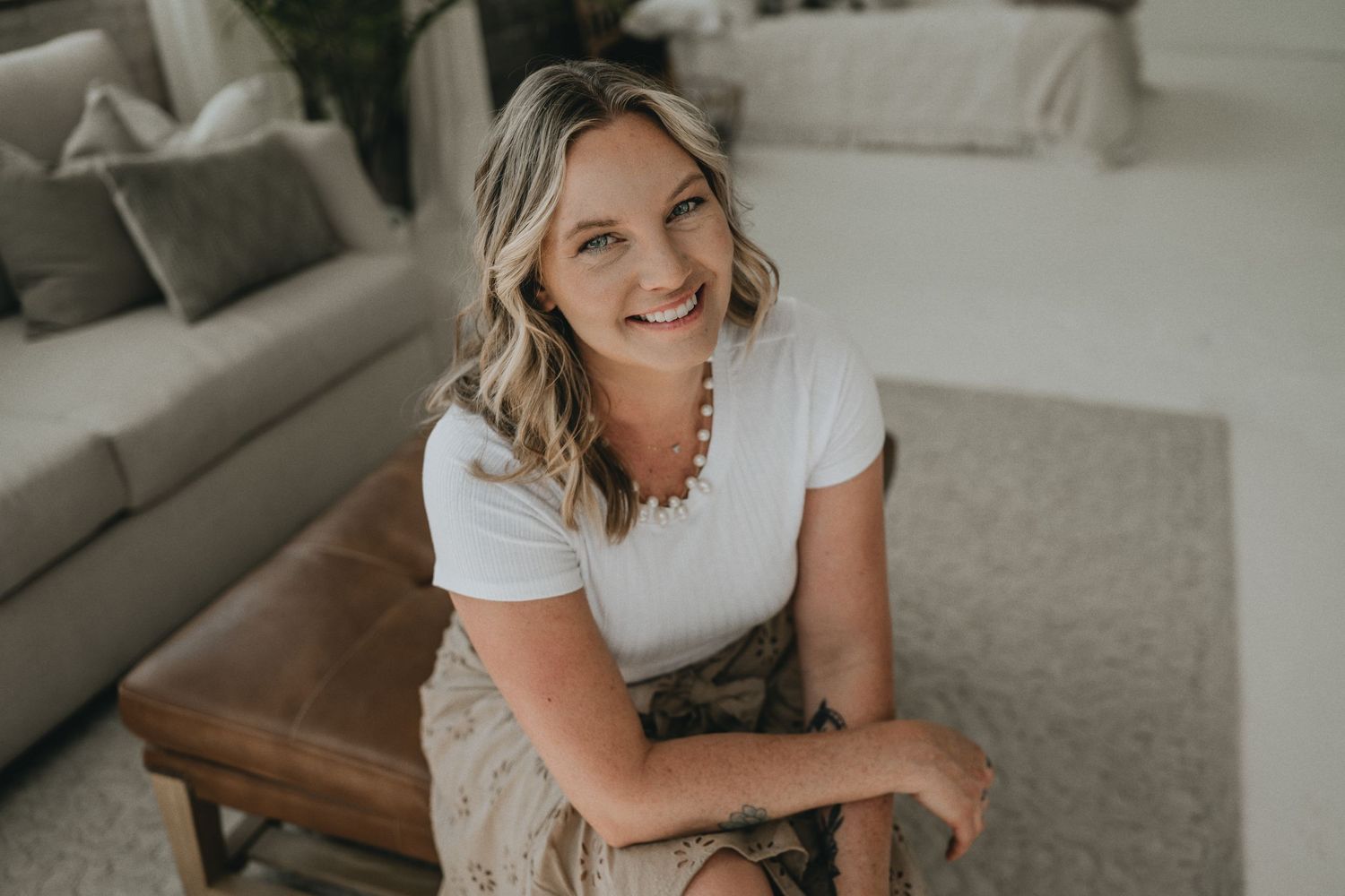 Person in casual white tee and beige pants relaxing in modern living space.