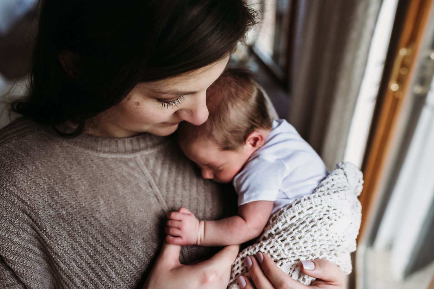 A nurturing moment of comfort and connection while wrapped in a soft knit blanket.