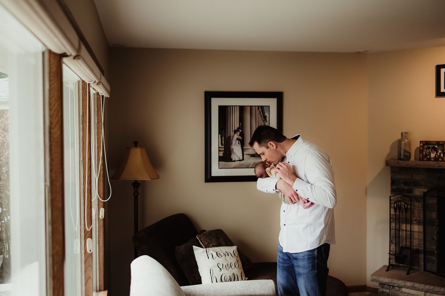 Person in white shirt standing by window in living room with beige walls.