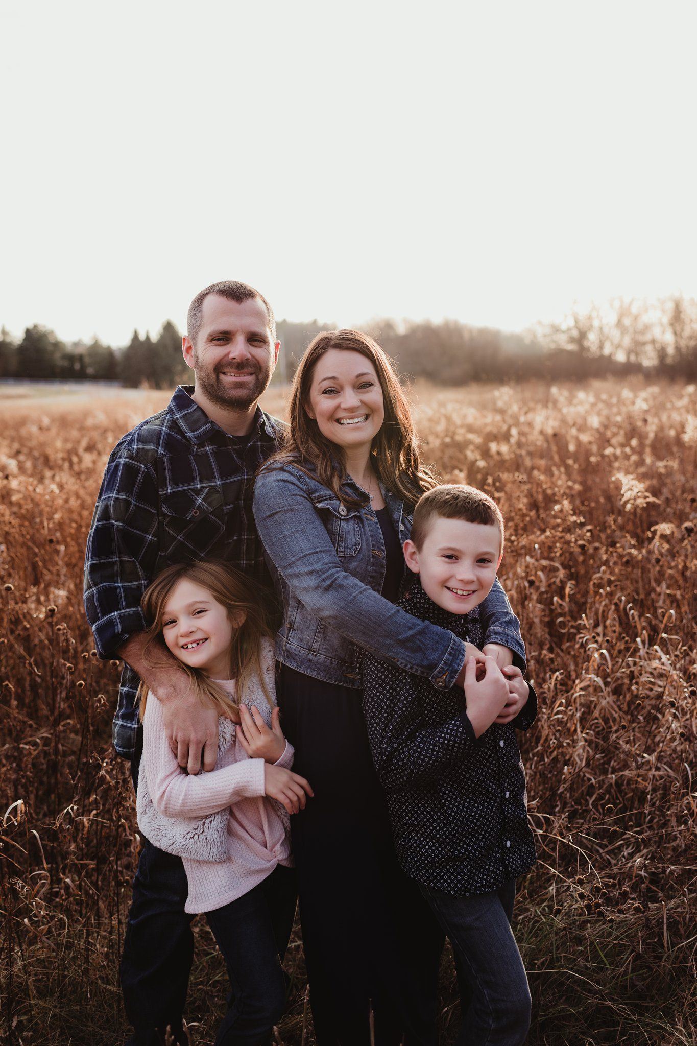 A loving family portrait in a rustic autumn field at golden hour.