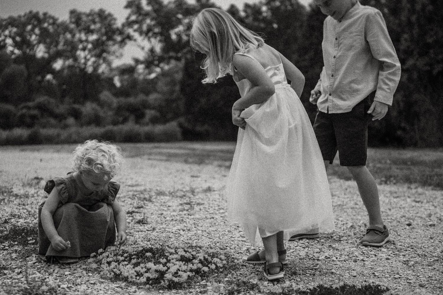 Children playing and exploring on gravel path in black and white photography.