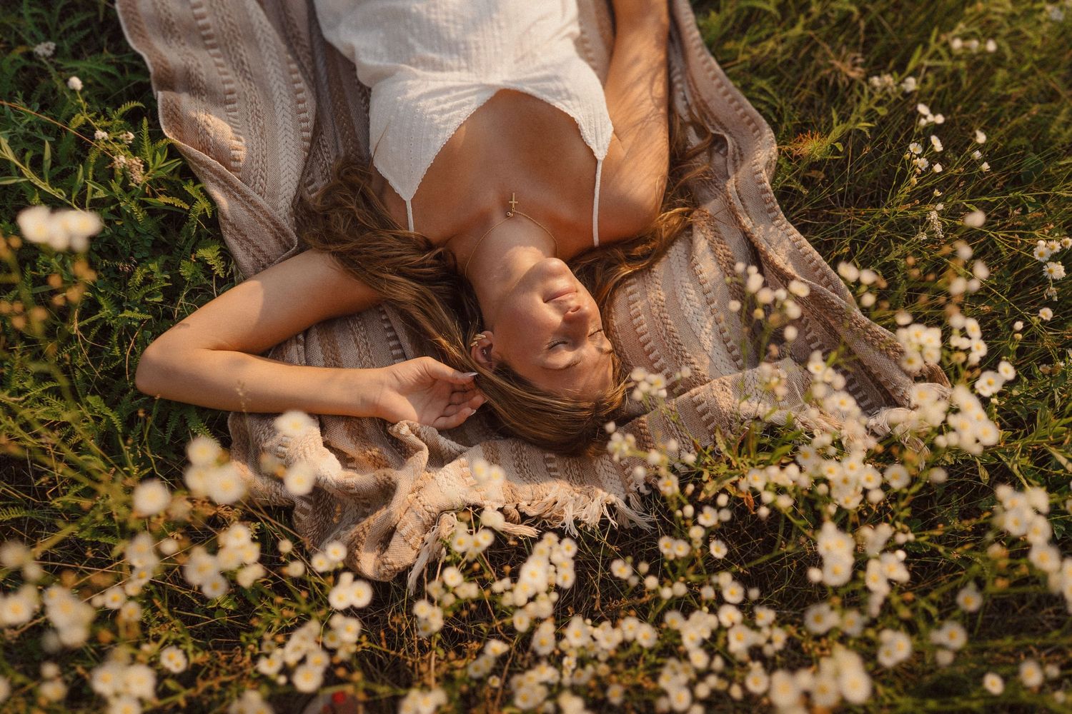 Dreamy outdoor portrait in field with white flowers during golden hour.