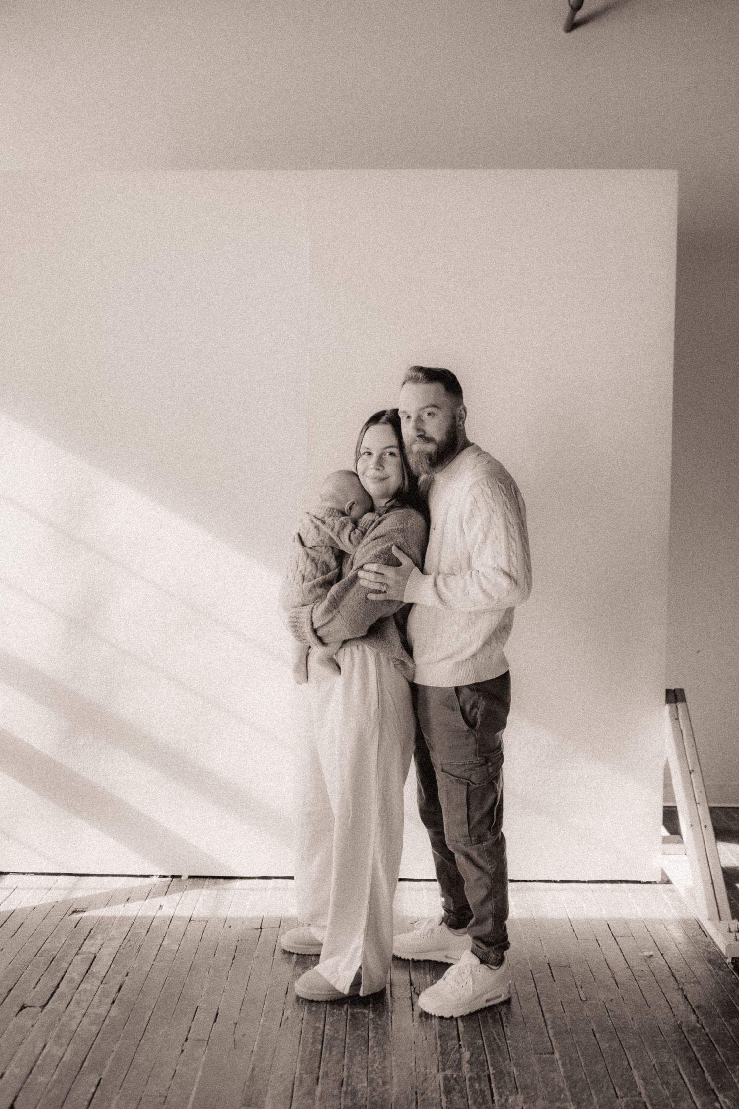 Artistic black and white photos showing couple in intimate poses against white wall.