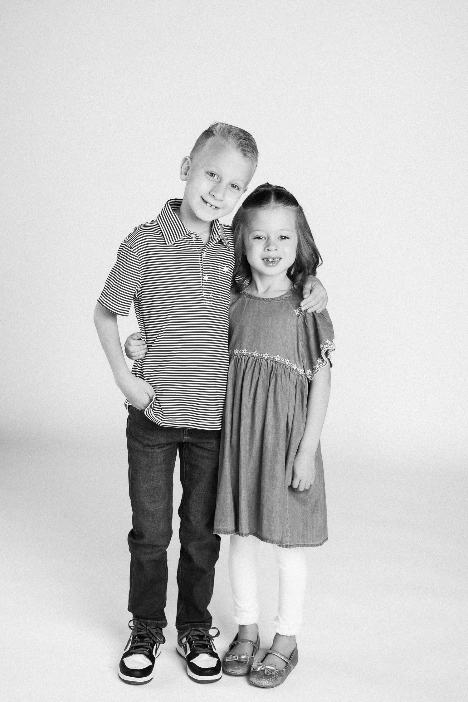 Black and white studio portraits showing two young children posing together in casual attire against a plain backdrop.