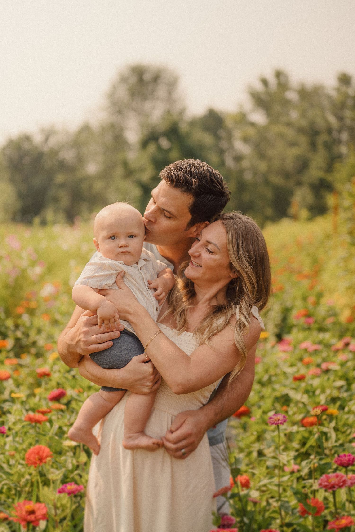 A tender family moment captured in a blooming flower field during sunset.