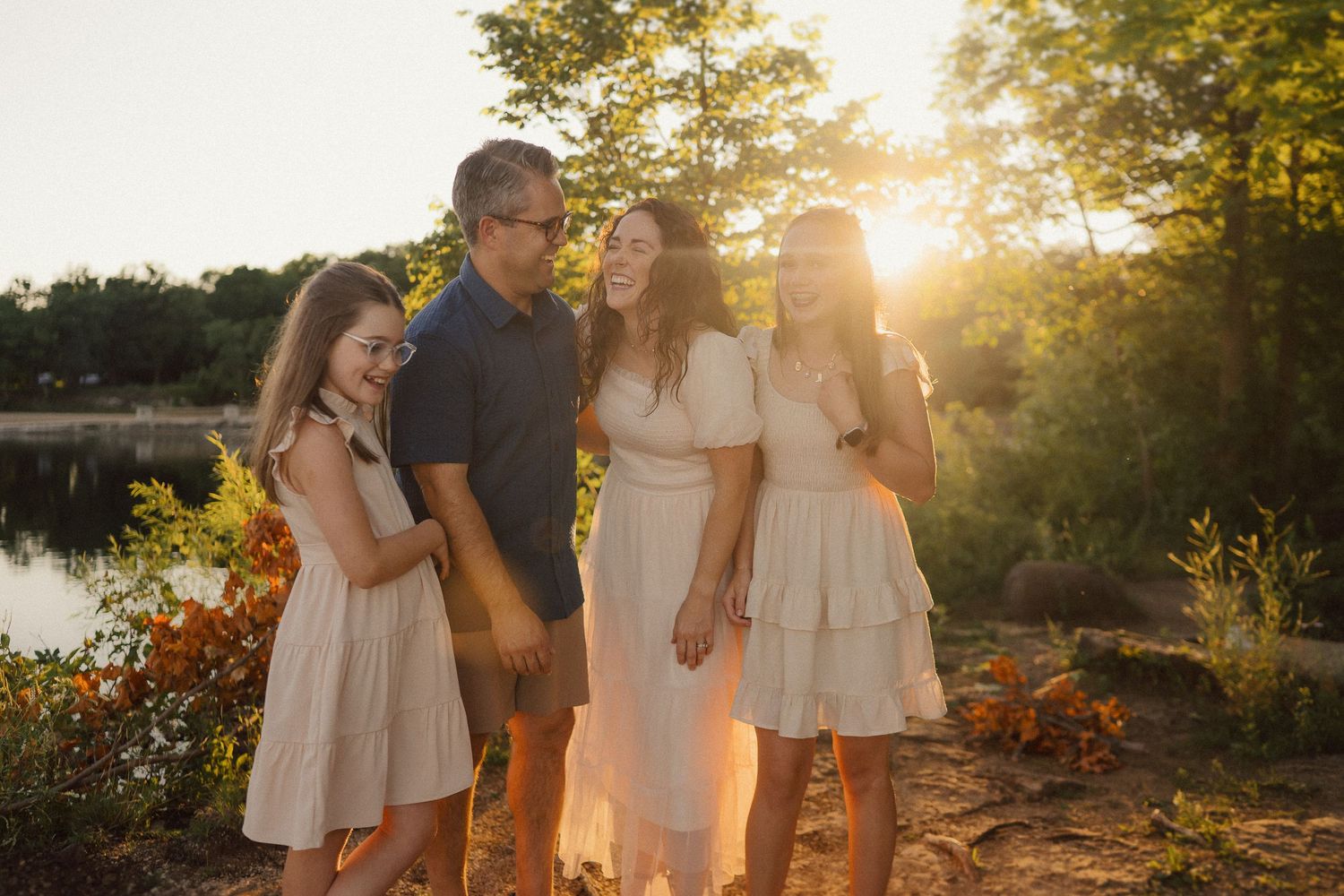 Family enjoying sunset by a lake wearing coordinated white and navy outfits.