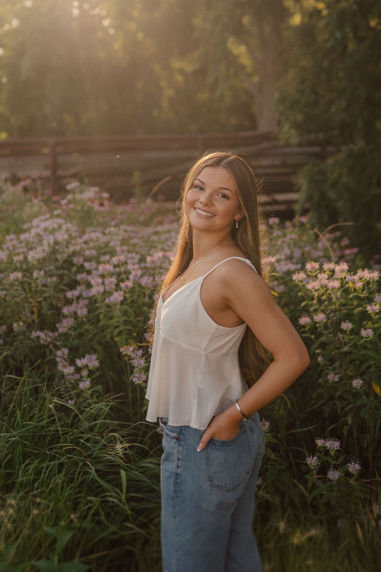 Candid outdoor photoshoot against a backdrop of pink blooming flowers at sunset.