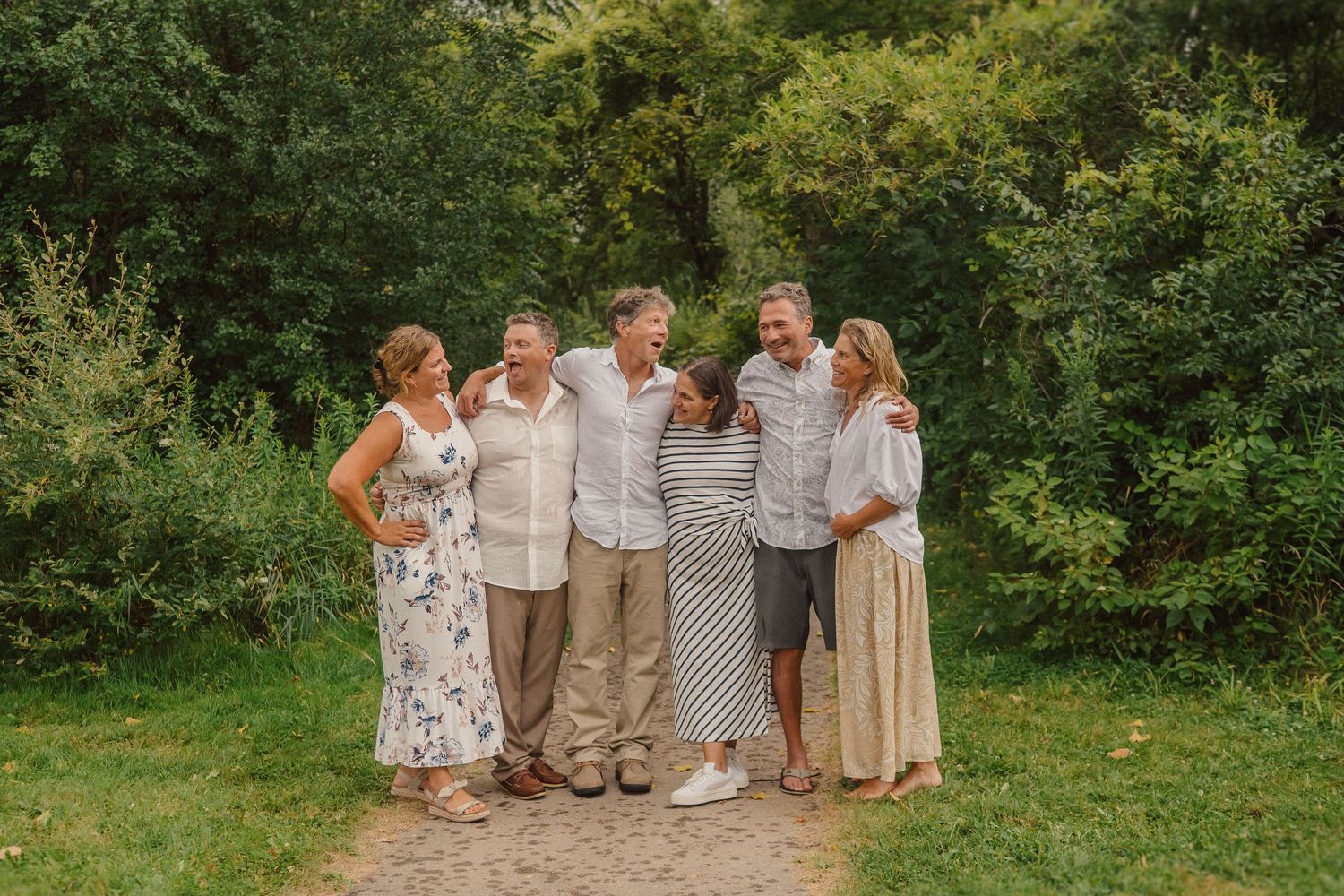 Group photo session in a natural setting with everyone dressed in coordinated earth-tone outfits.