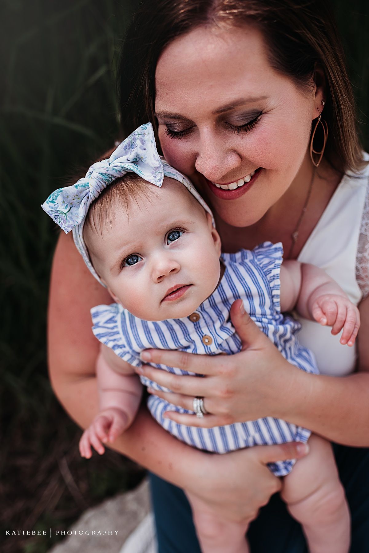 Close-up portrait showing tender moment between caregiver and baby in striped outfit.