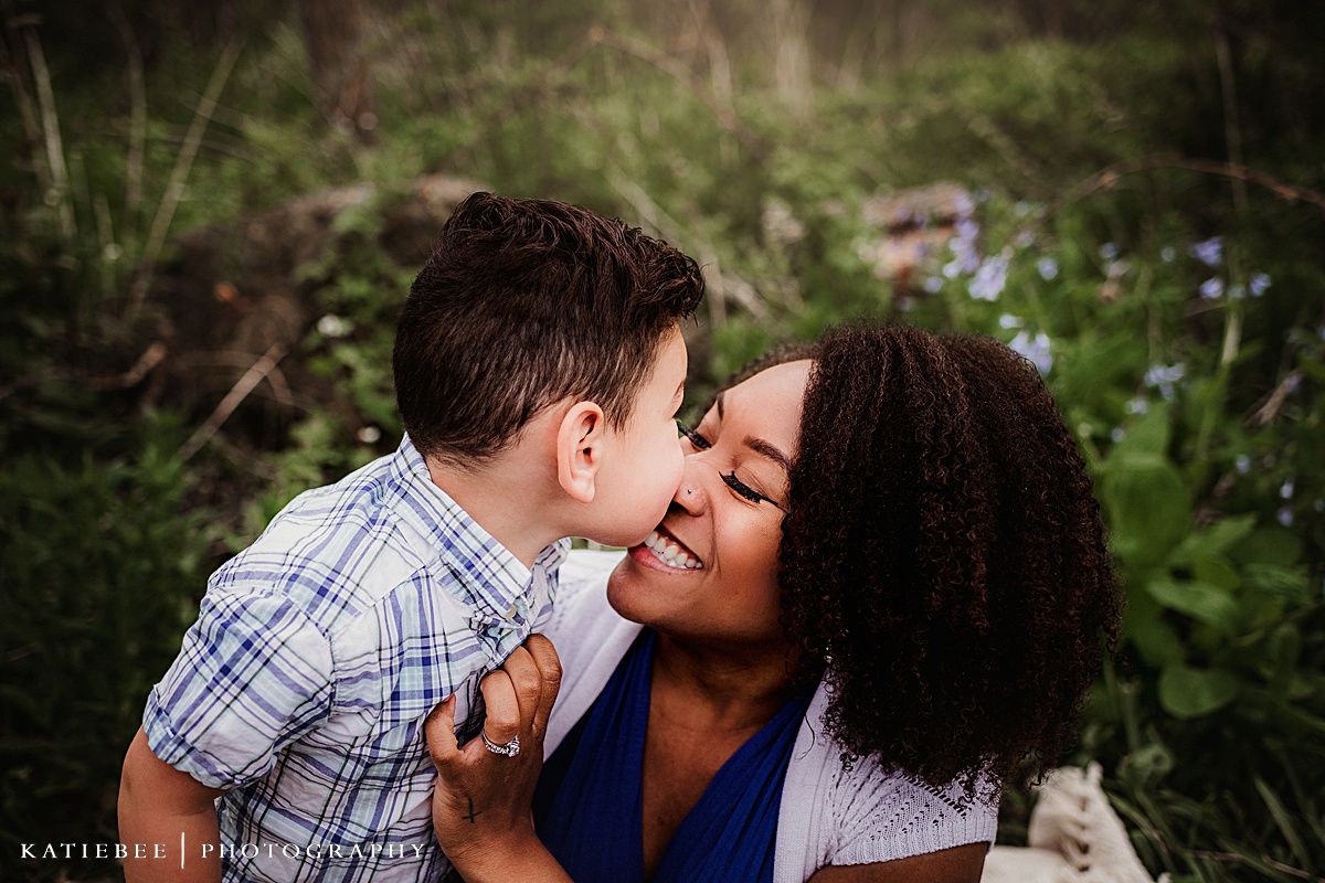 Tender outdoor portrait of a mother and young child sharing an intimate moment among wildflowers.