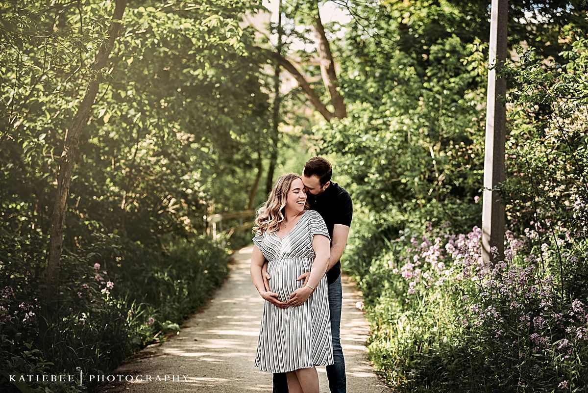 Romantic maternity portrait of couple on a tree-lined path.