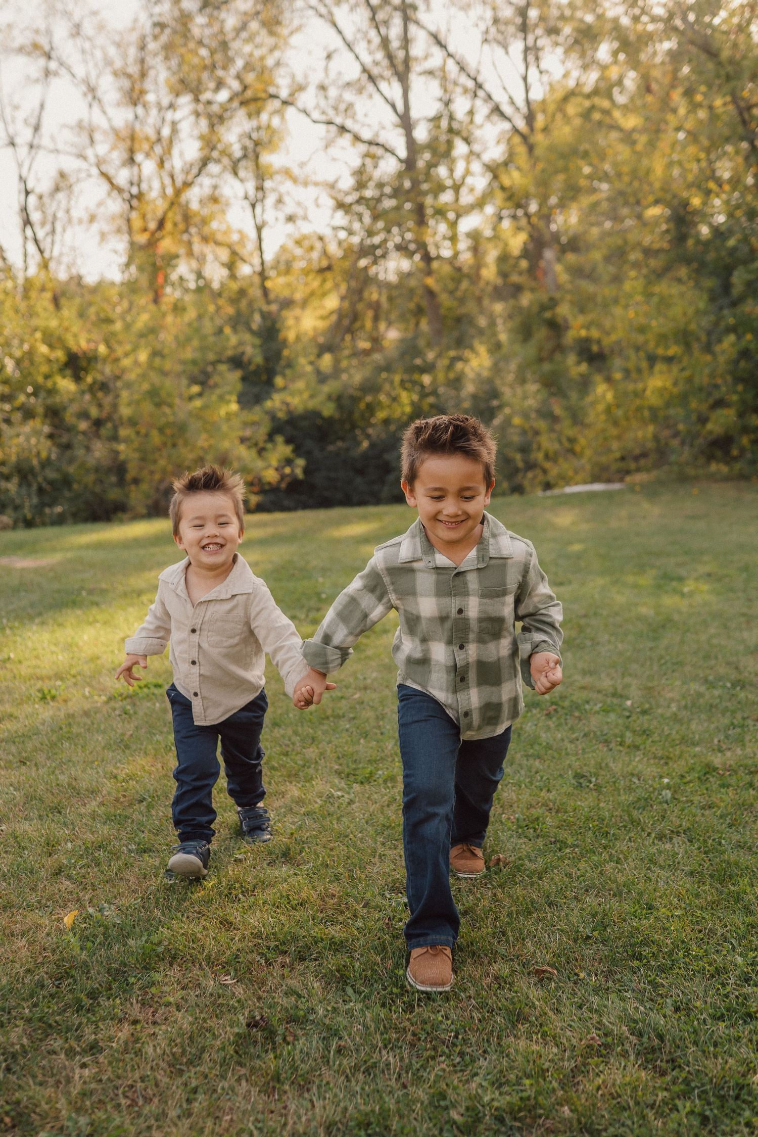 Children running and playing together on a grassy hill during autumn.