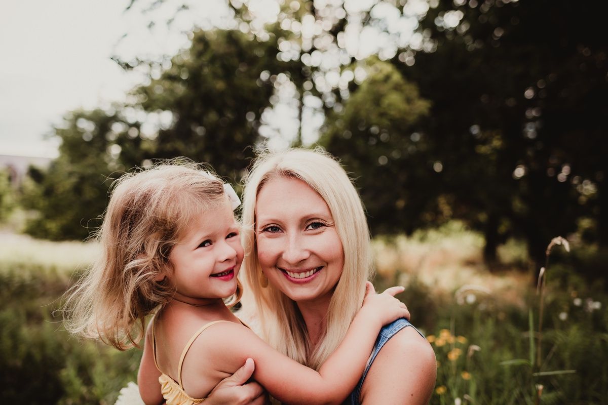 A candid portrait of parent and child sharing laughter in a summer meadow.