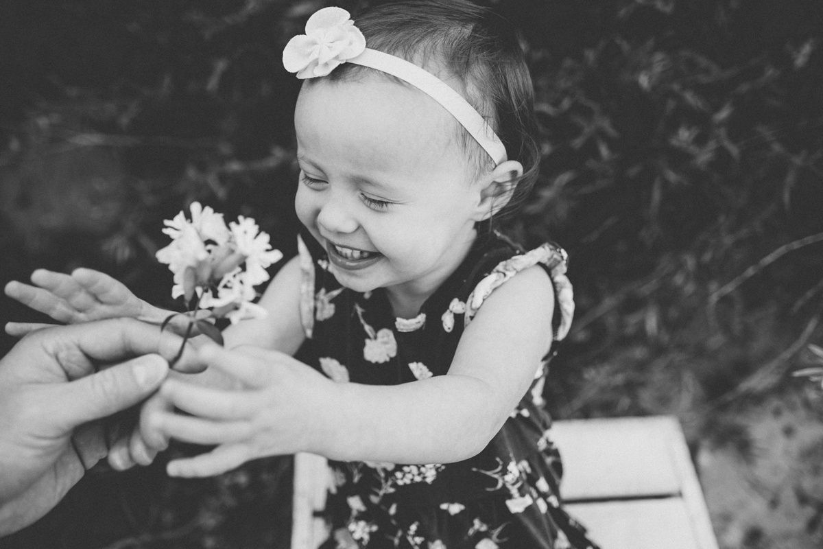 Black and white photo of a delightful moment as a small child receives a flower.
