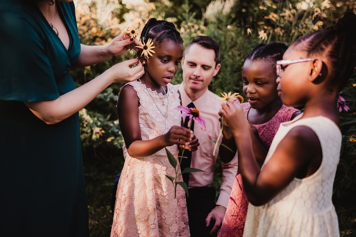 A joyful outdoor gathering where people interact while holding small flowers in a garden.