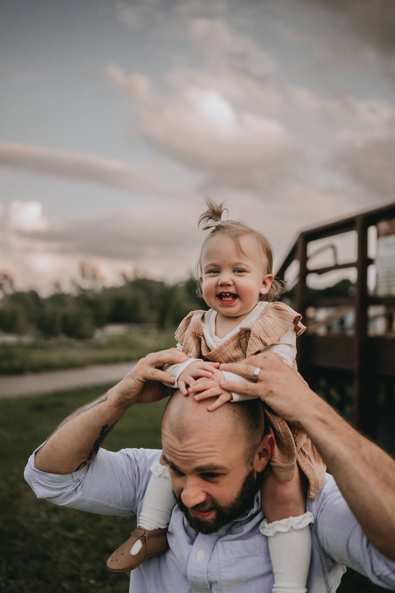 Joyful playtime outdoors with a shoulder ride in the golden evening light.