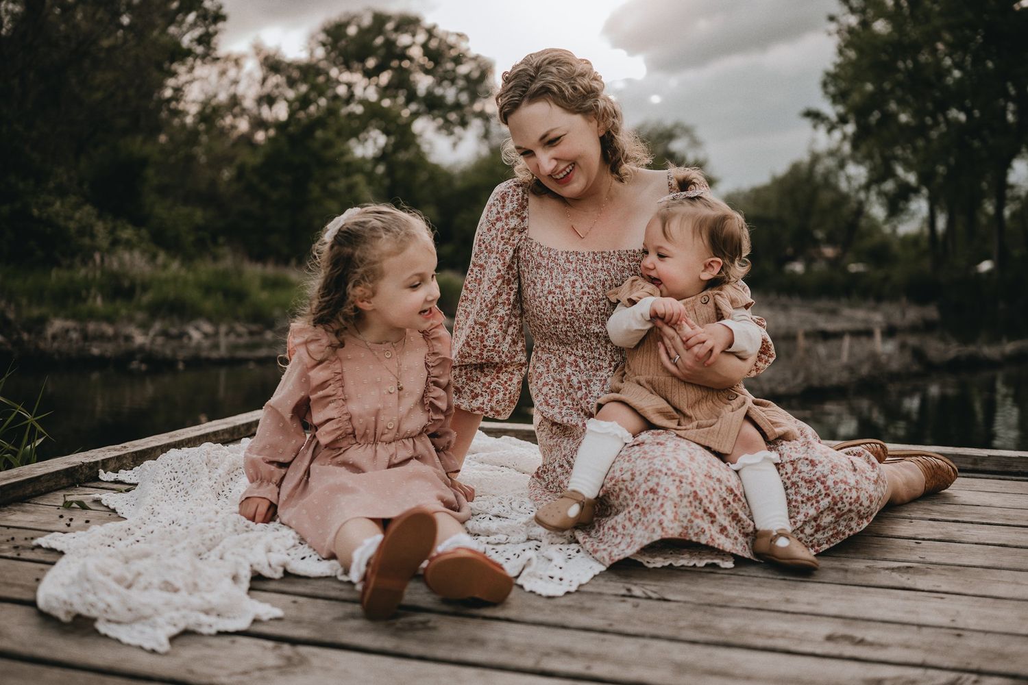 An intimate family portrait on a wooden dock during sunset.