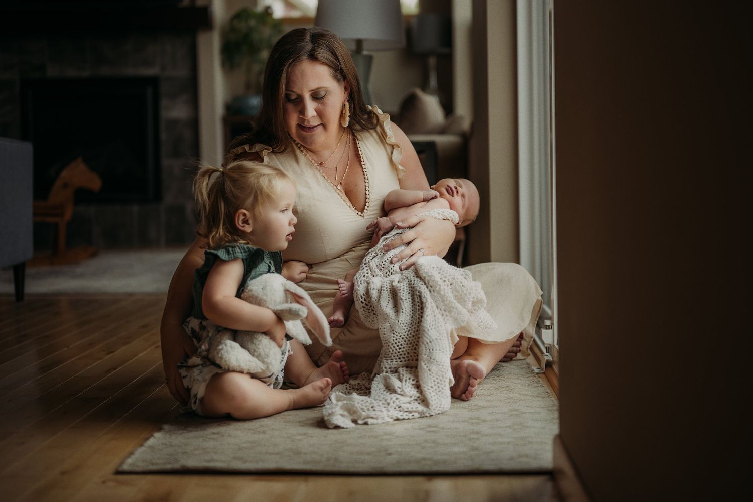 Intimate family moment captured on floor by window with soft natural lighting.
