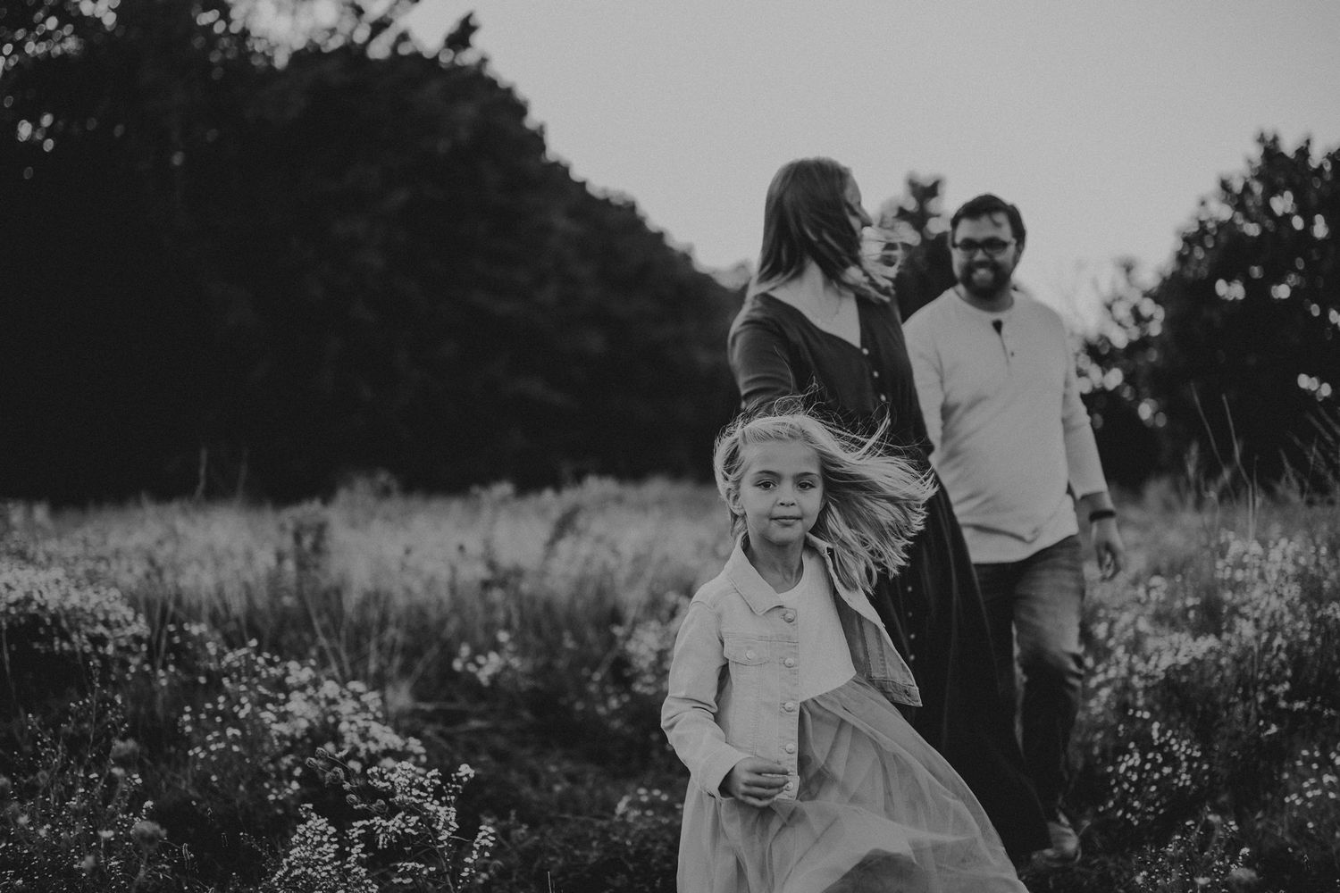 Family enjoying a candid moment together in a wildflower meadow at sunset.