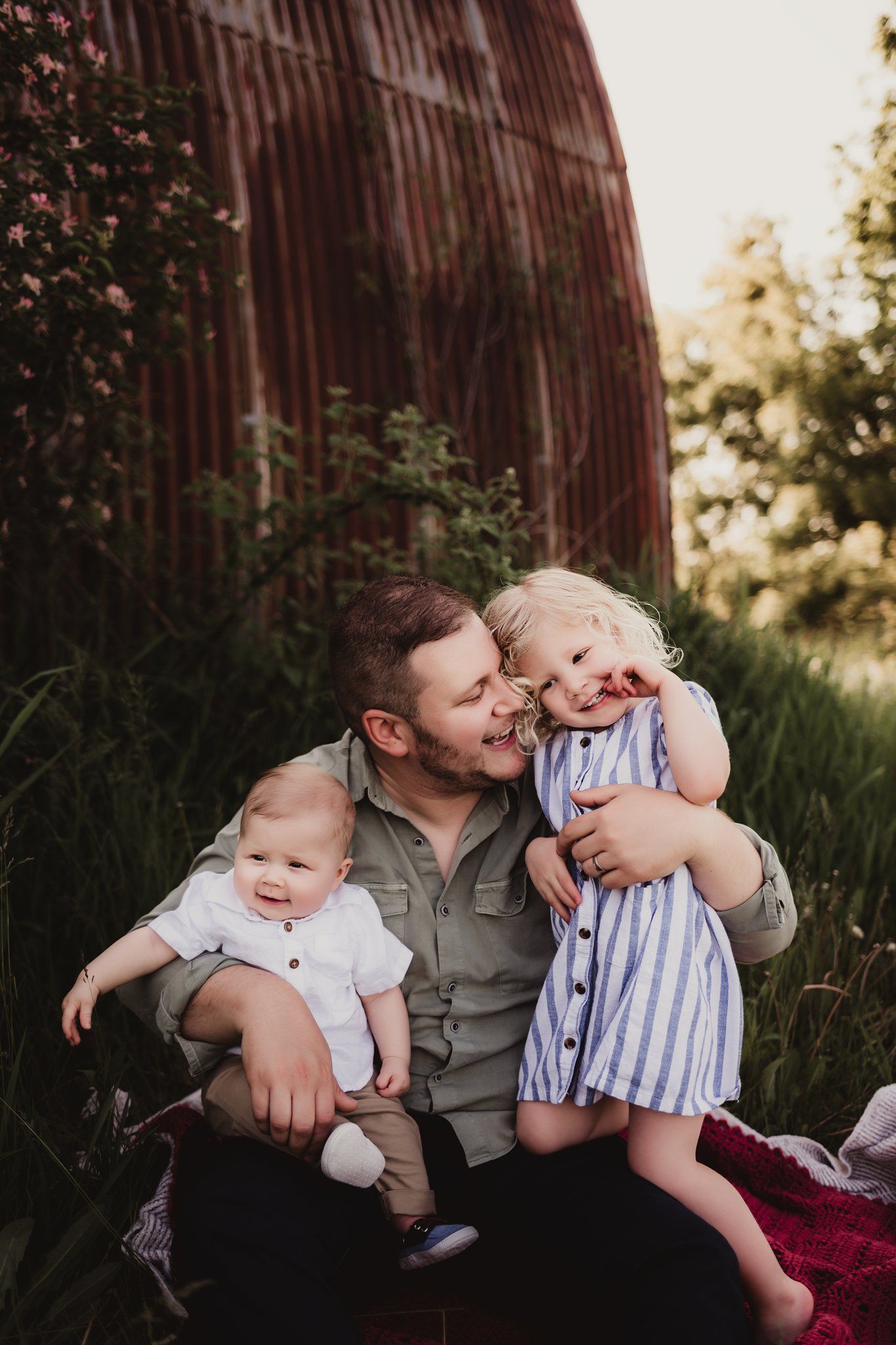 A candid family moment showing affection and laughter outside a rustic barn.