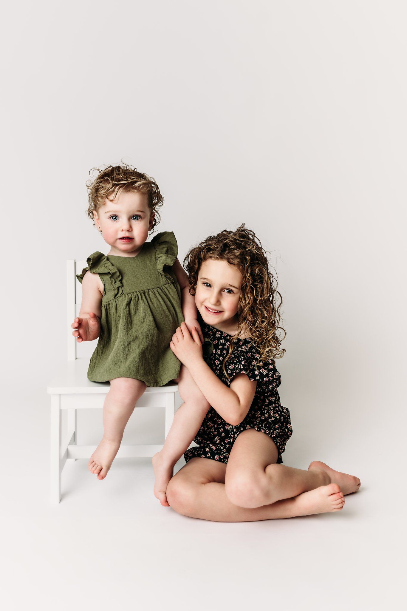 A candid portrait of two children posing together against a white background.