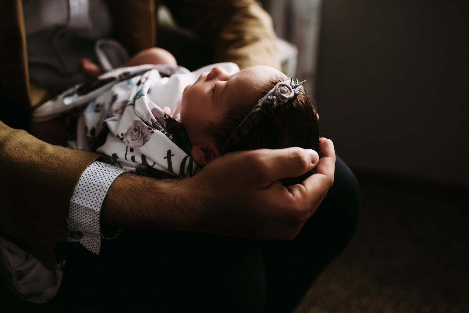 Close-up of sleeping infant being carefully held in gentle hands.