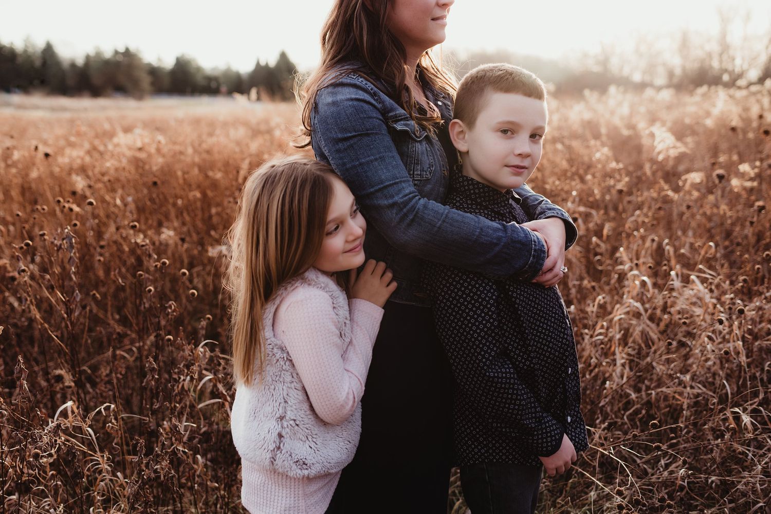 A candid family moment together outdoors in a golden field during sunset.