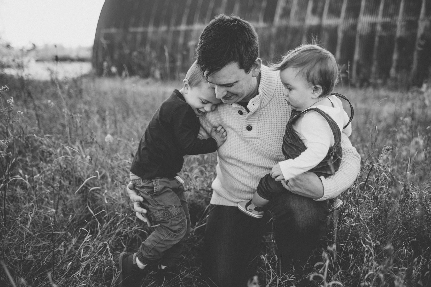 An intimate black and white family portrait in a natural outdoor setting.