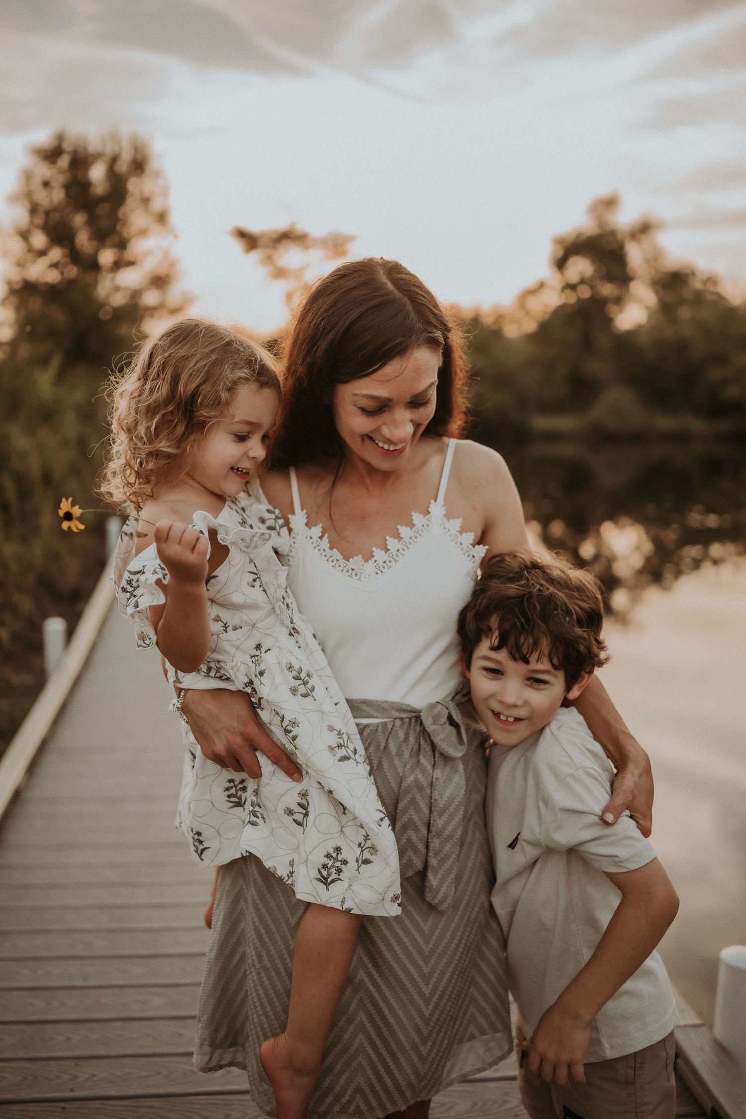 A heartwarming sunset family moment captured on a wooden dock over calm water.