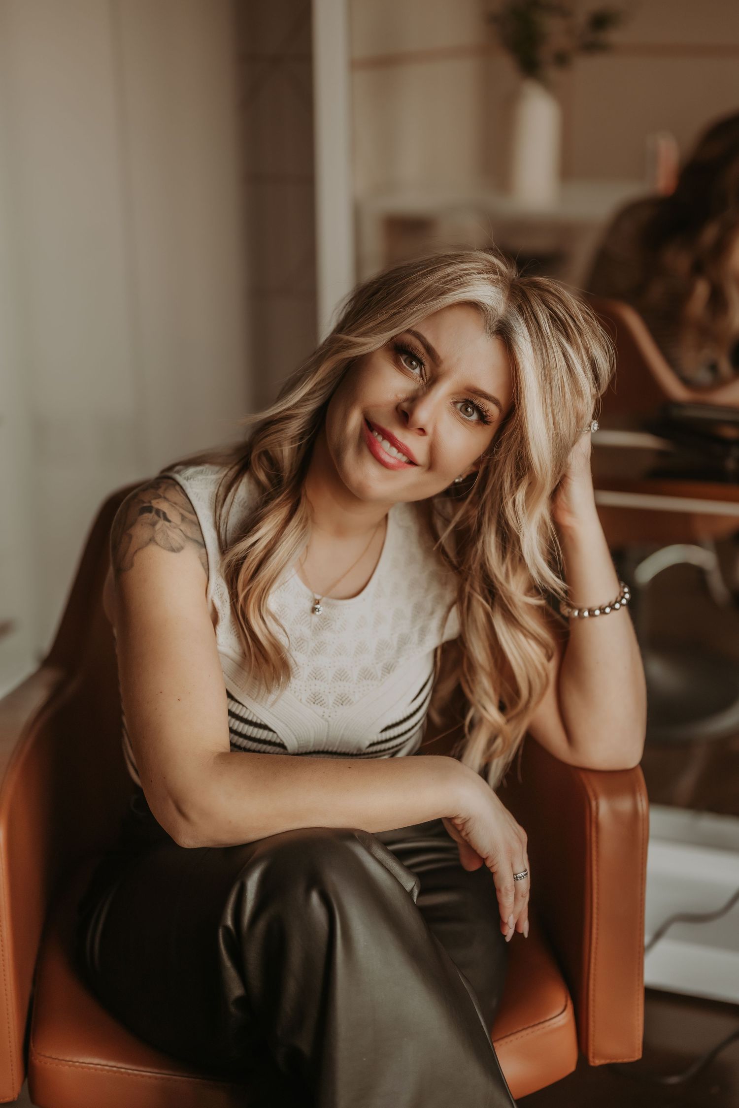 Casual portrait in an orange armchair showcasing business casual attire in a warm-toned interior setting.