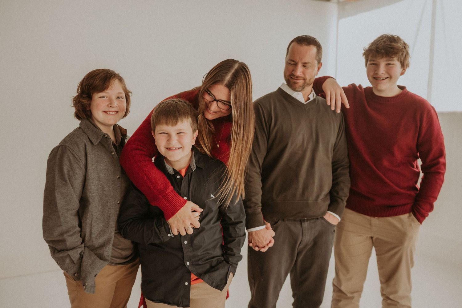 Casual family group photo with members wearing coordinated sweaters and earth-toned clothing.