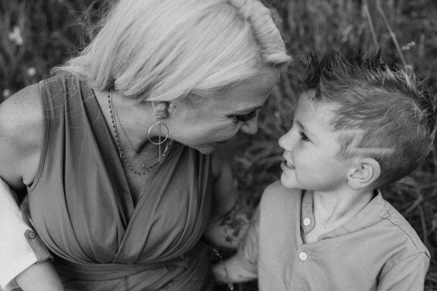 A black and white close-up portrait showing a tender moment between two people.