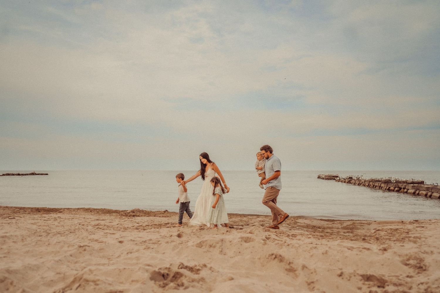 Family walks together on a sandy beach during golden hour.