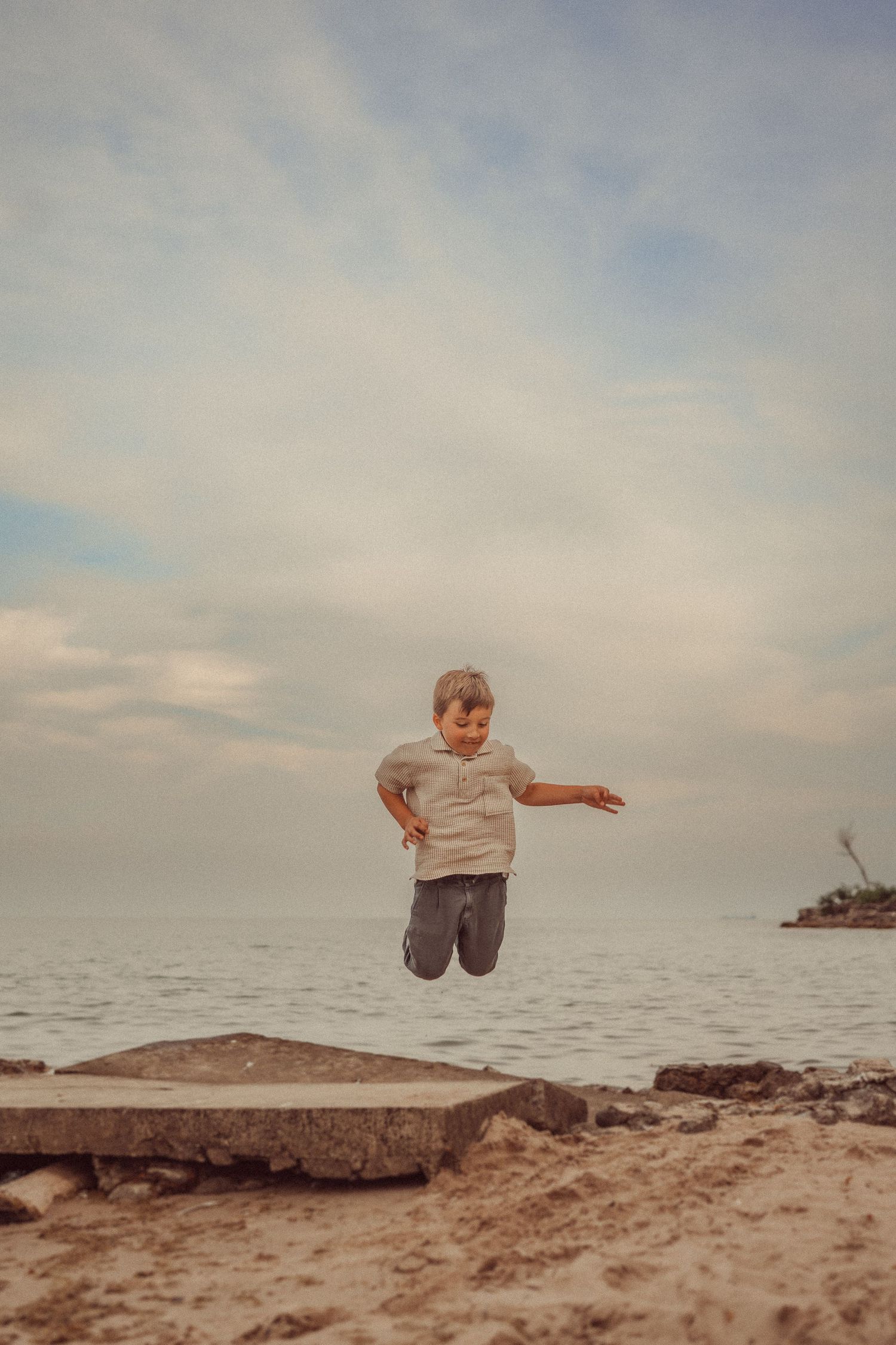 An energetic mid-jump photo captured against cloudy skies and ocean waves.