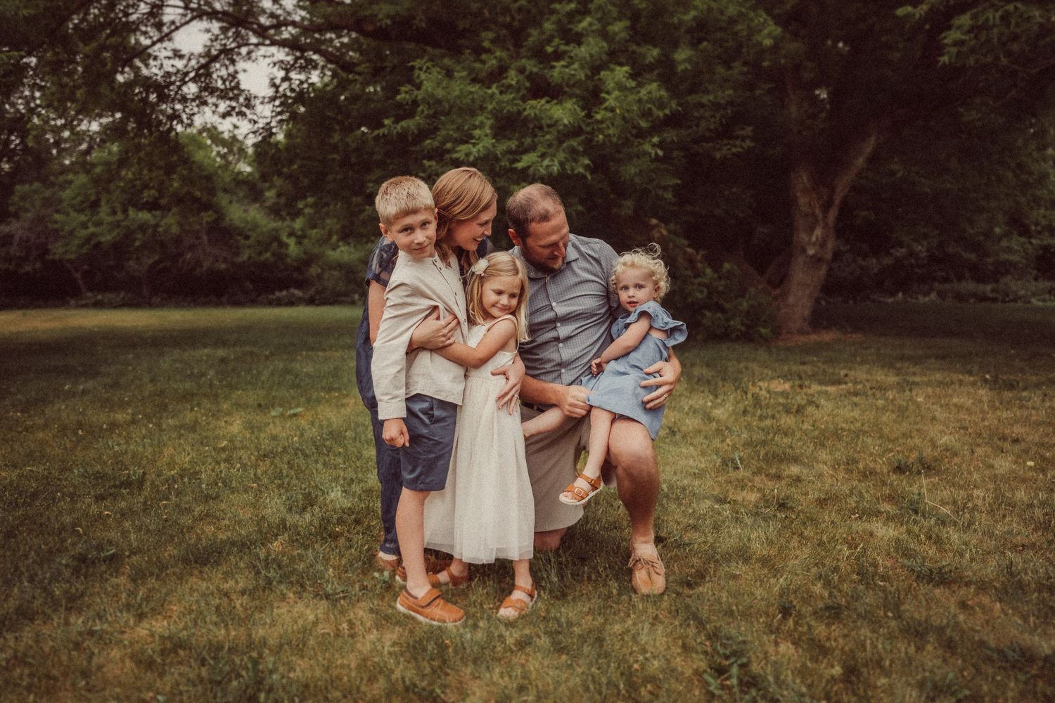 Intimate family portrait captured outdoors in a casual setting during sunset.