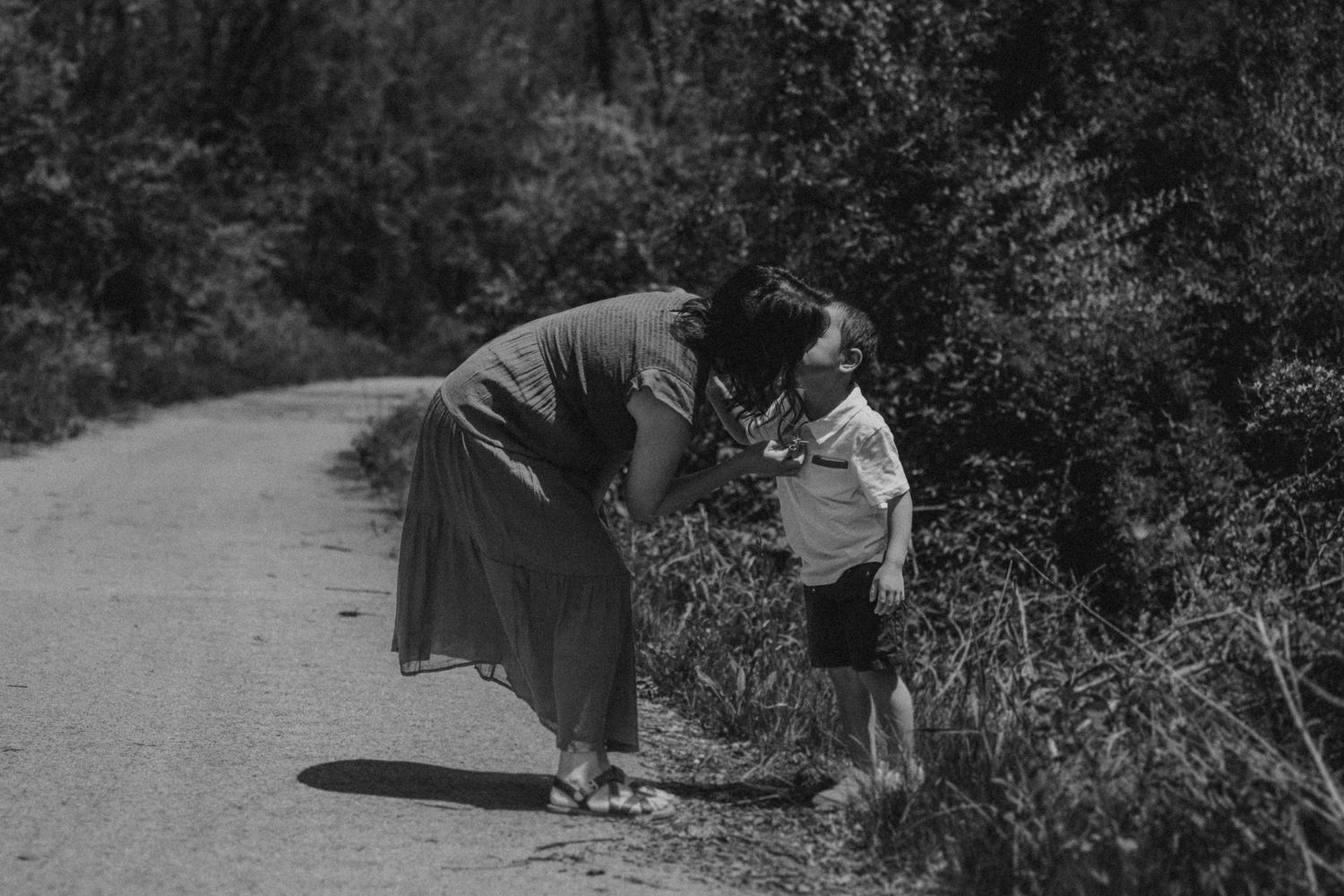 A tender moment captured in black and white on a winding forest path.