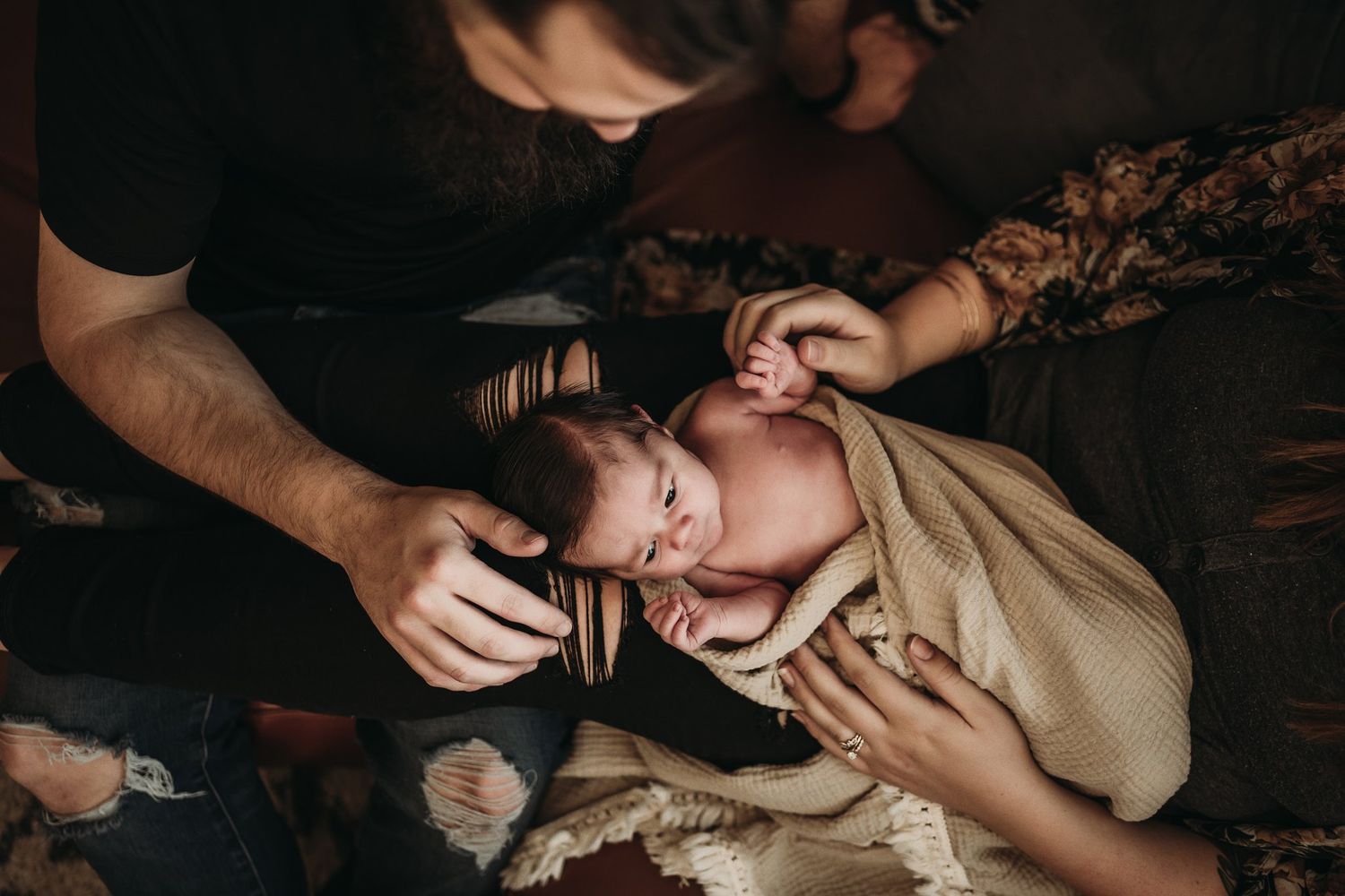 Candid moment of parents holding newborn baby during lifestyle photo session.