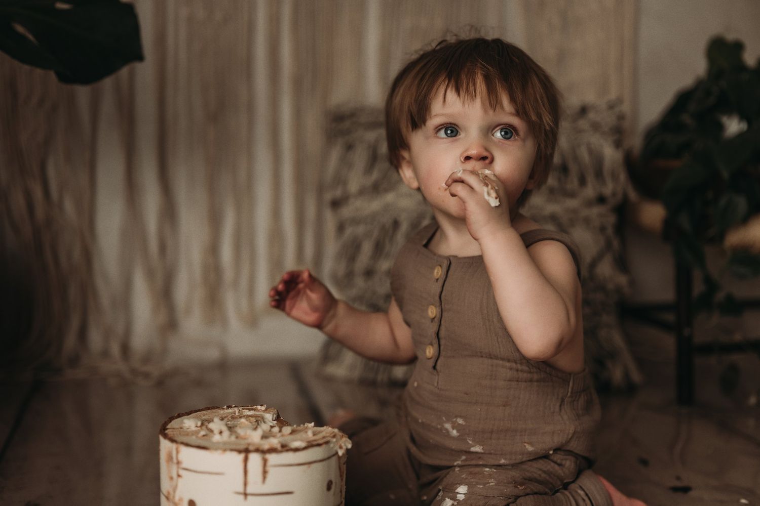 A woodland-themed cake smash session with destroyed white cake and rustic decorations.
