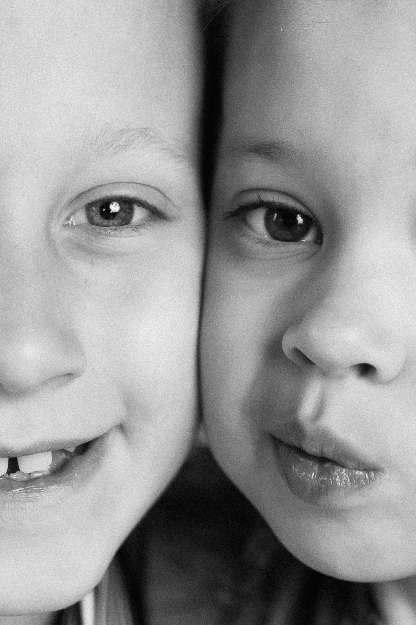 A black and white close-up portrait of two young children's faces side by side.