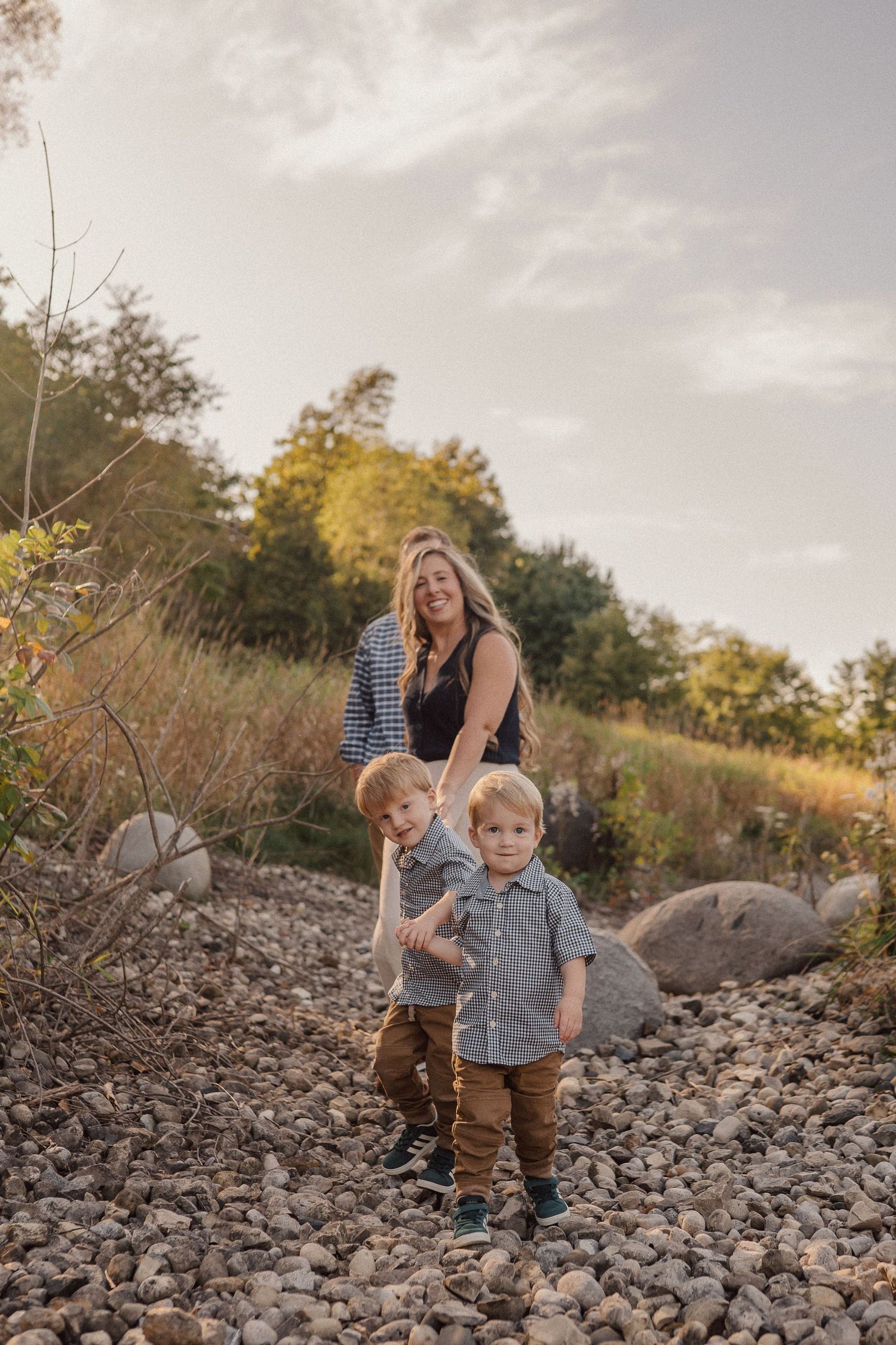 A family enjoying playtime together on a rocky terrain during golden hour with trees in the background.